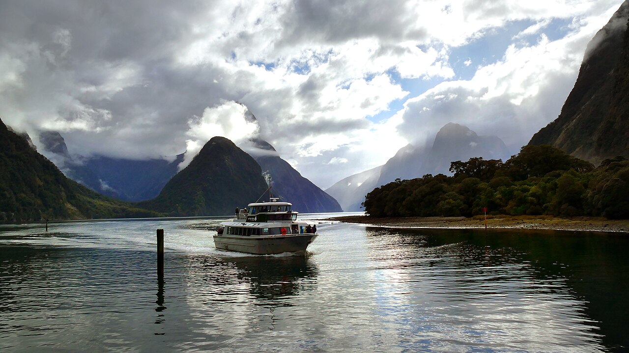 A sightseeing boat cruising beneath the mountains of Milford Sound